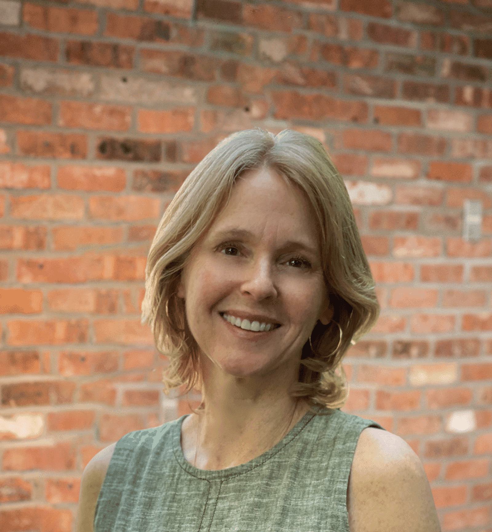 Elizabeth Gish's headshot with a brick wall in the background