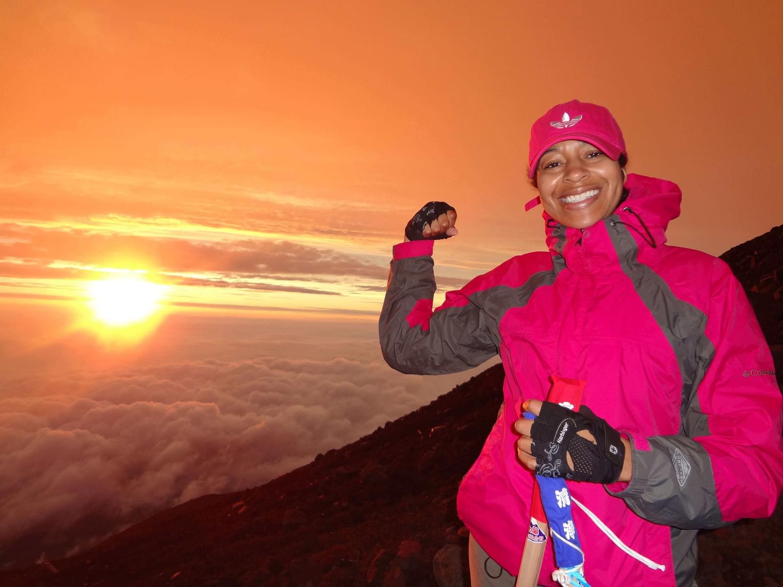 Elyce Middlebrooks posing in front of sun on summit of mountain