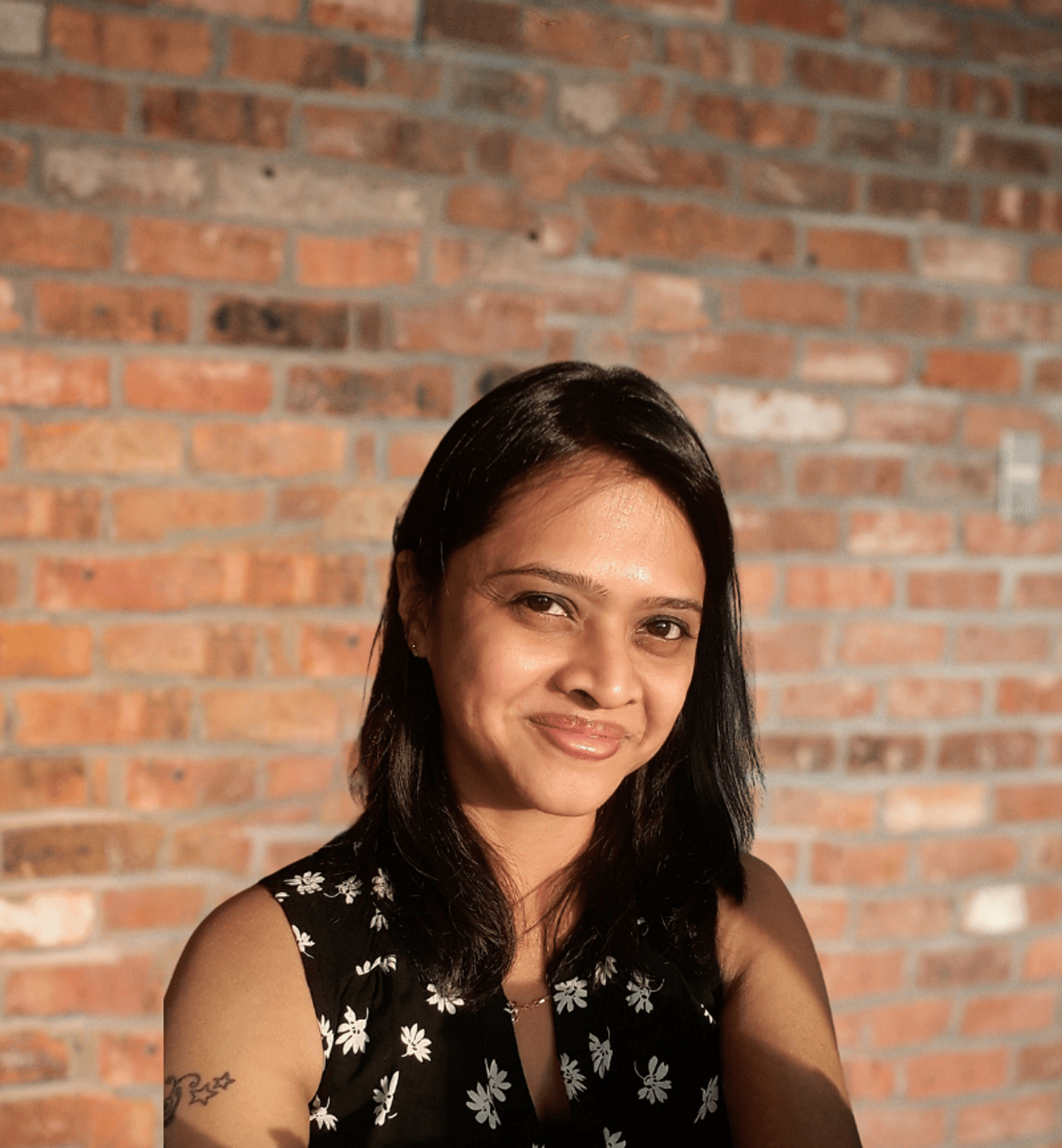 Kavita Rao Bawankar's headshot with a brick wall in the background