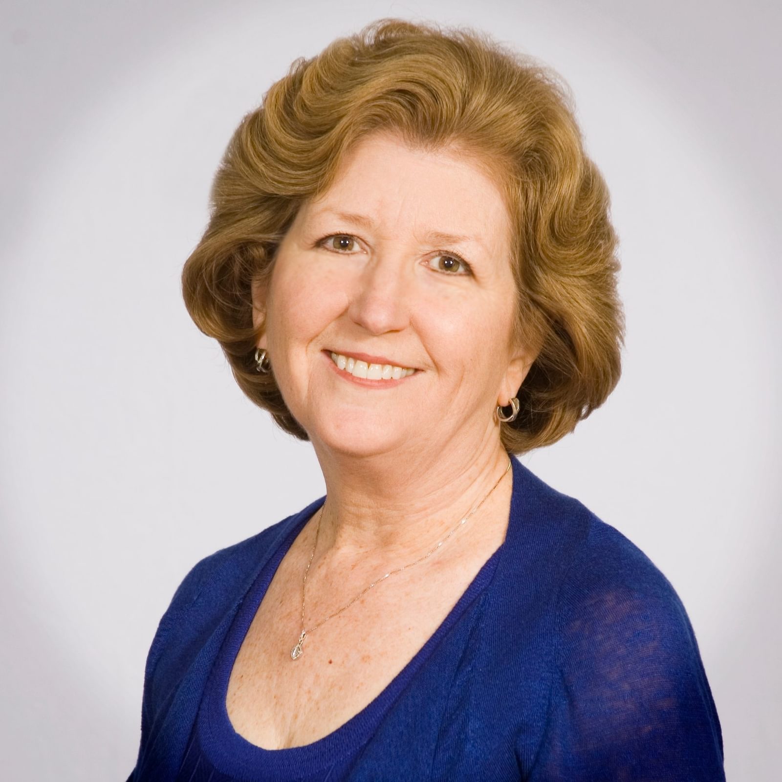 Mary Beth Barrett Newman smiling in a headshot wearing a blue shirt