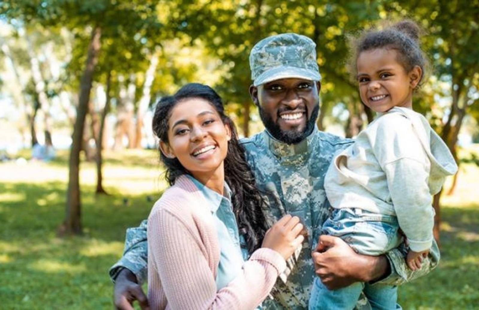 Man in miltary fatigues holding child with arm around spouse
