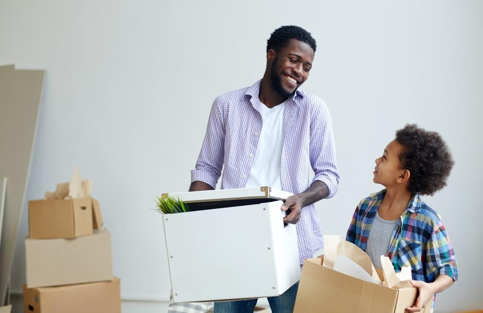 Father smiling at child as they move boxes in new house