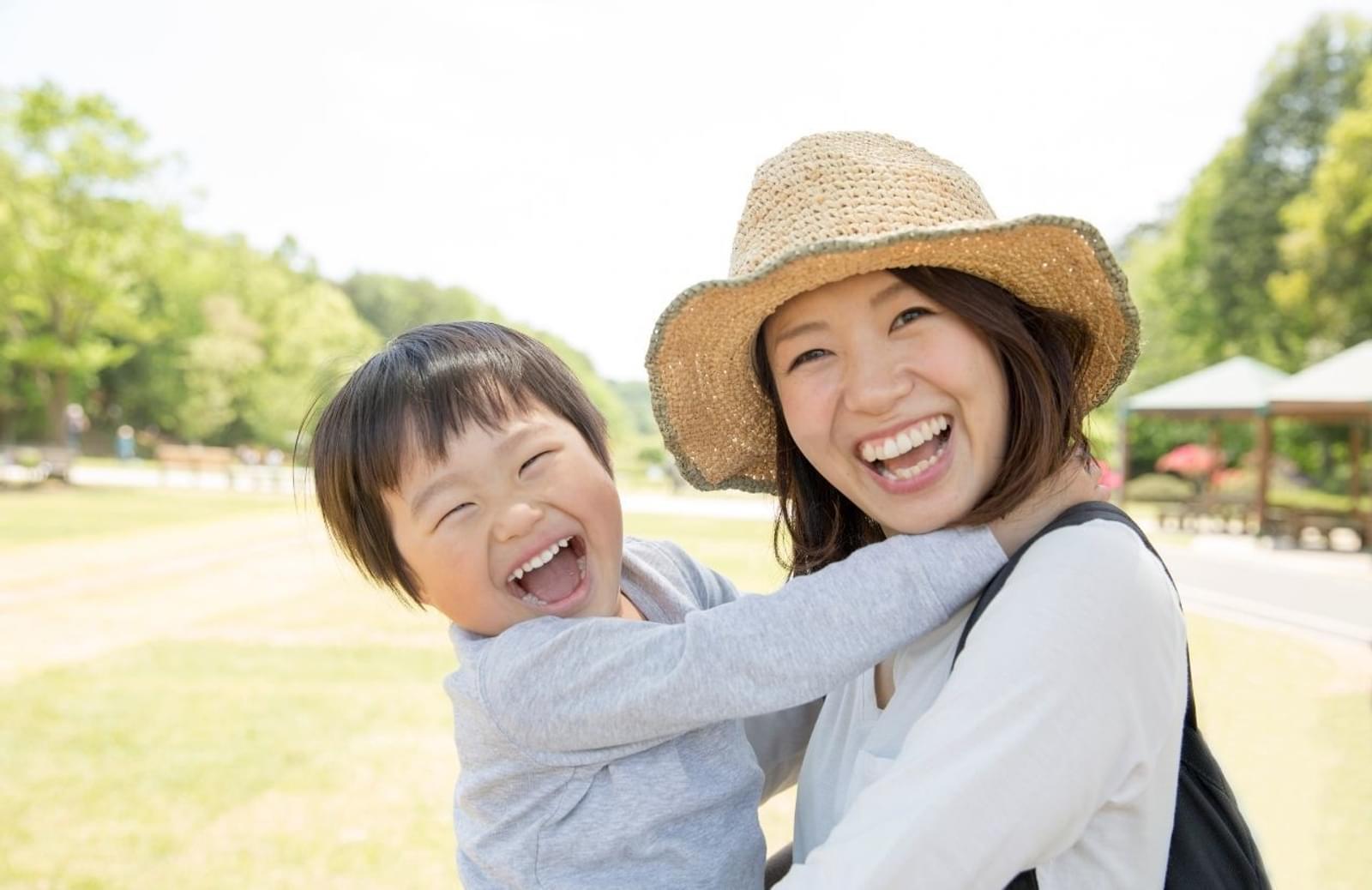 Asian woman smiling while holding smiling son