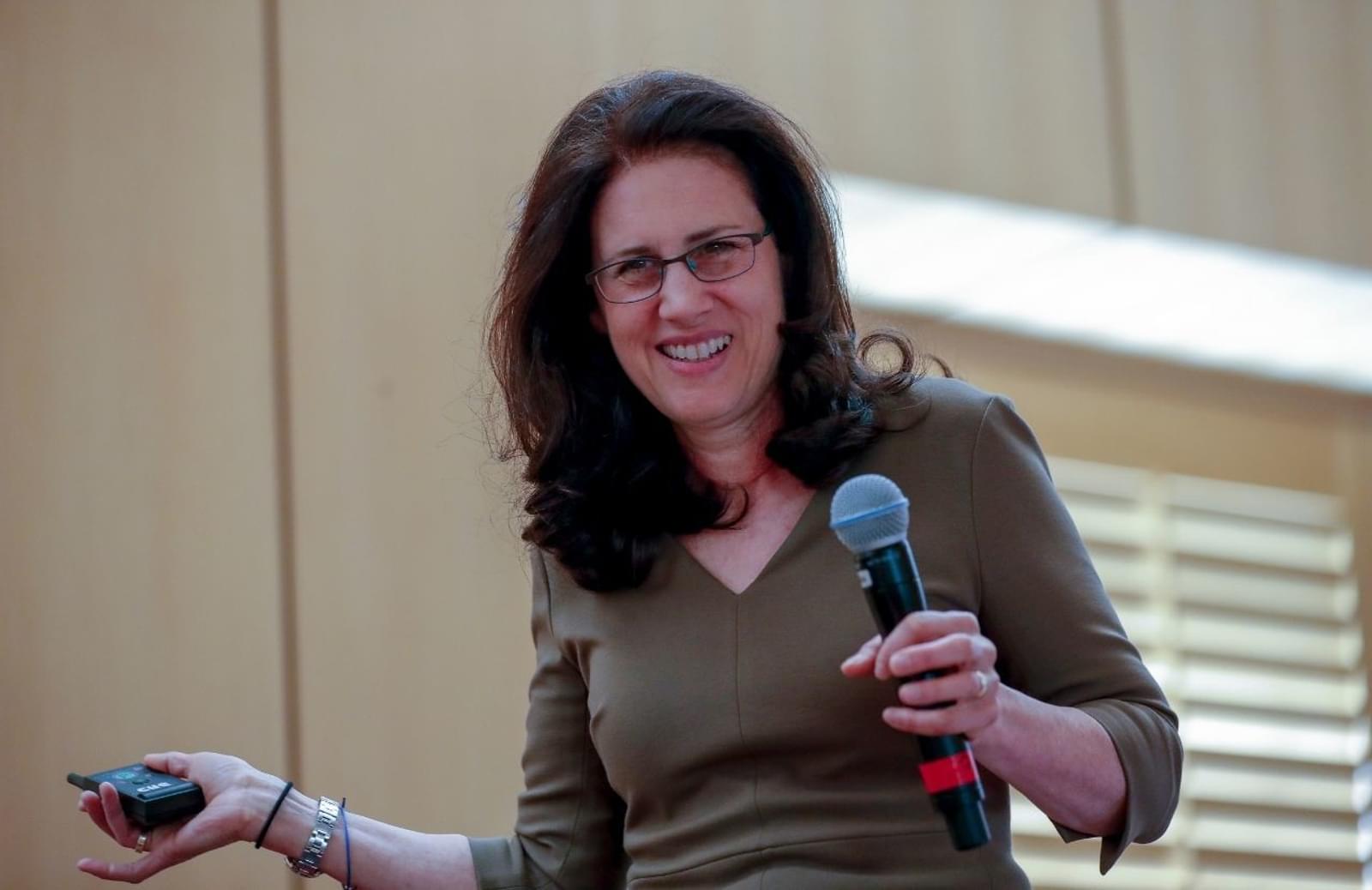 iRelaunch CEO and Co-Founder Carol Fishman Cohen holding microphone and smiling