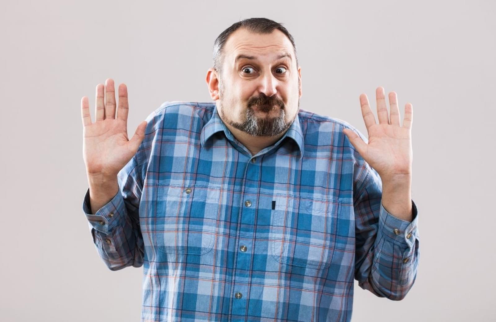 Man in plaid shirt standing with arms raised at elbows
