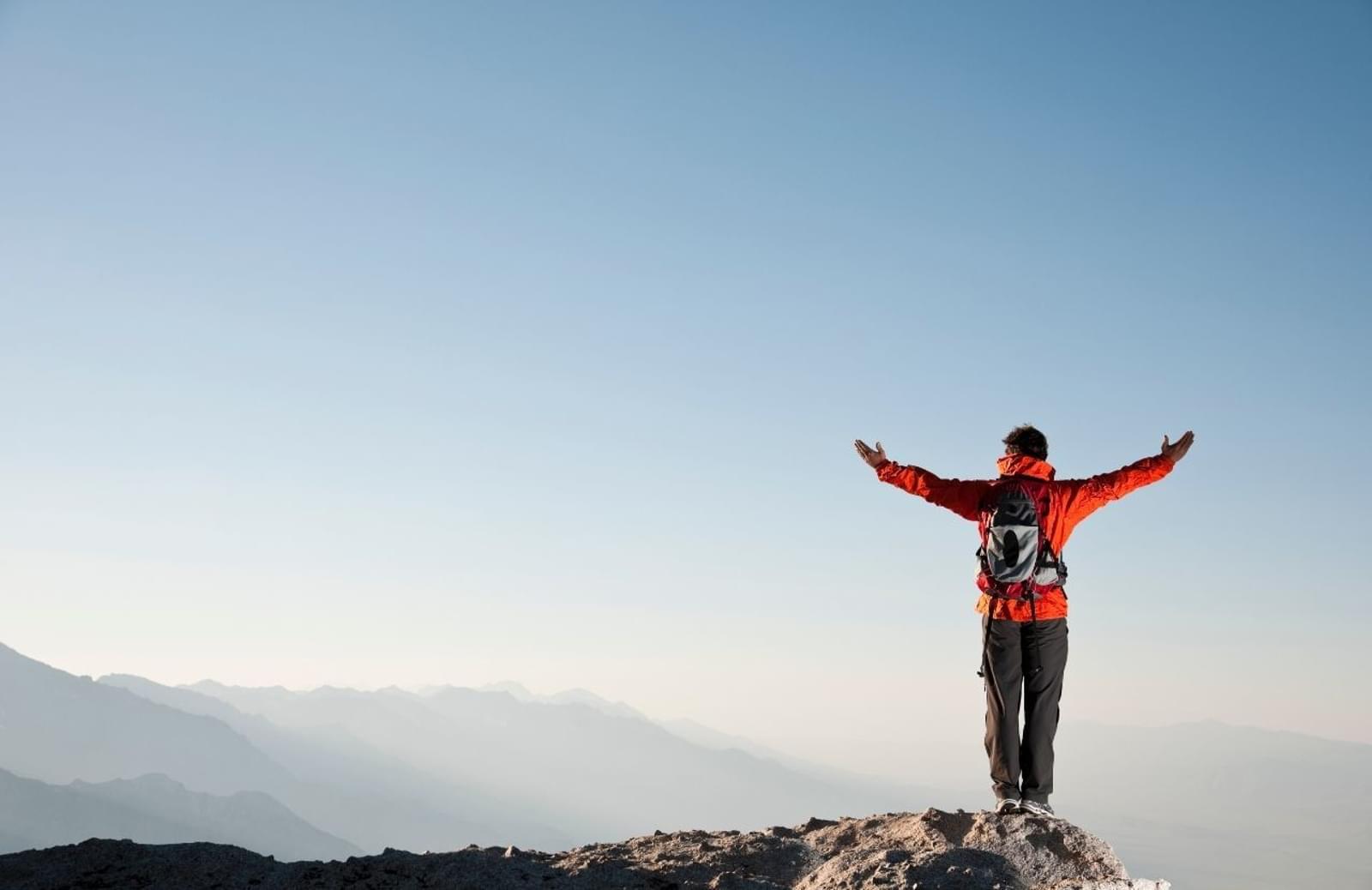 Person standing on mountain summit with outstretched arms