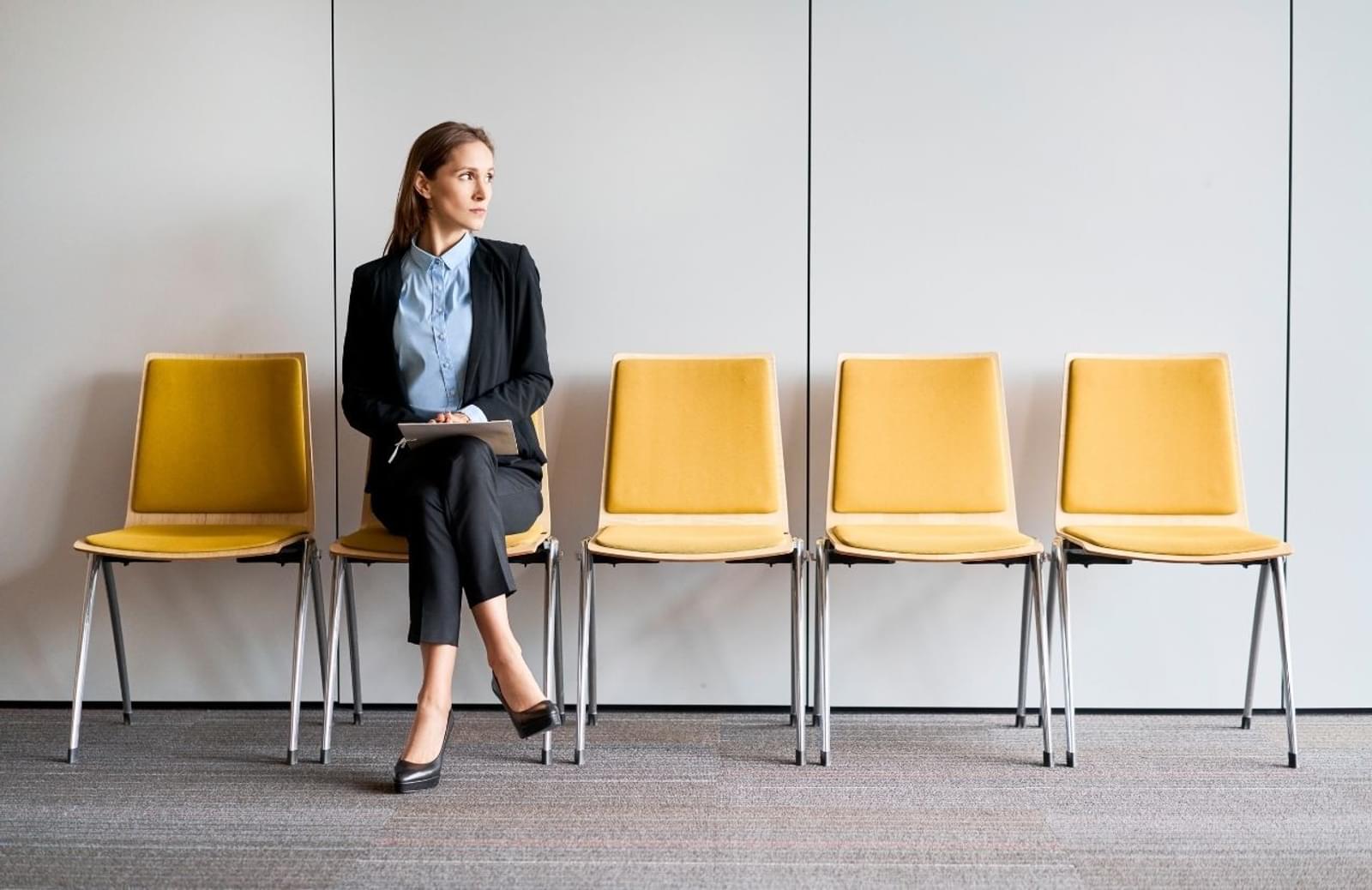 Woman sitting in a row of enpty chairs