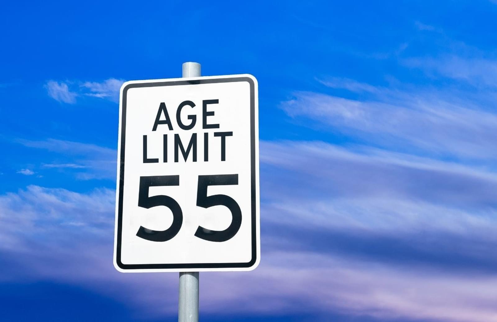 Street sign reading "Age Limit 55" against a blue sky