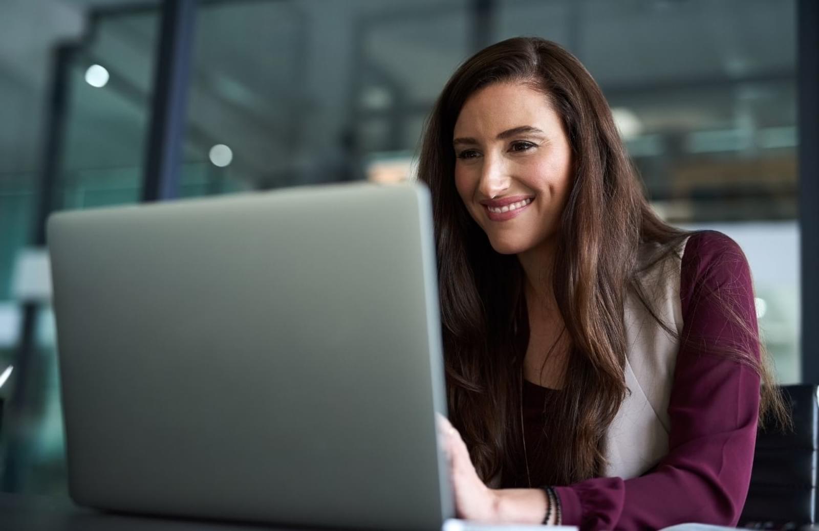 Woman smiling as she looks at laptop computer screen