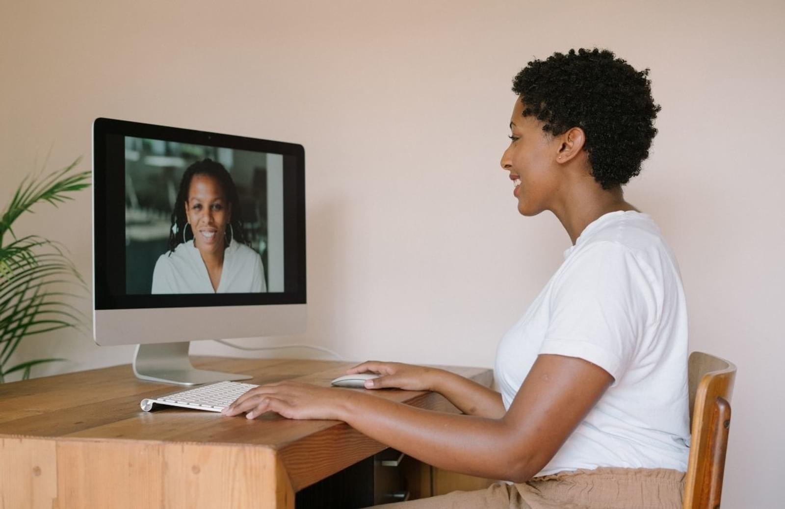 Woman at desk talking to another woman on her computer screen during virtual meeting
