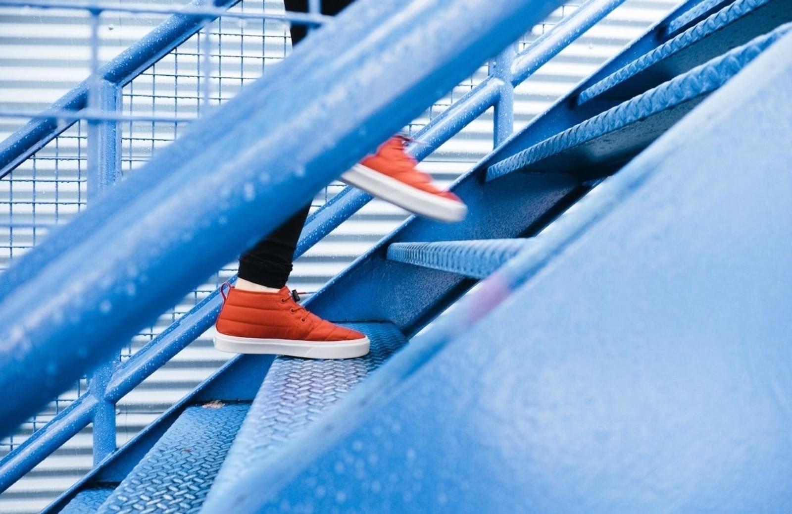 Person in red hig-top tennis shows ascending blue staircase
