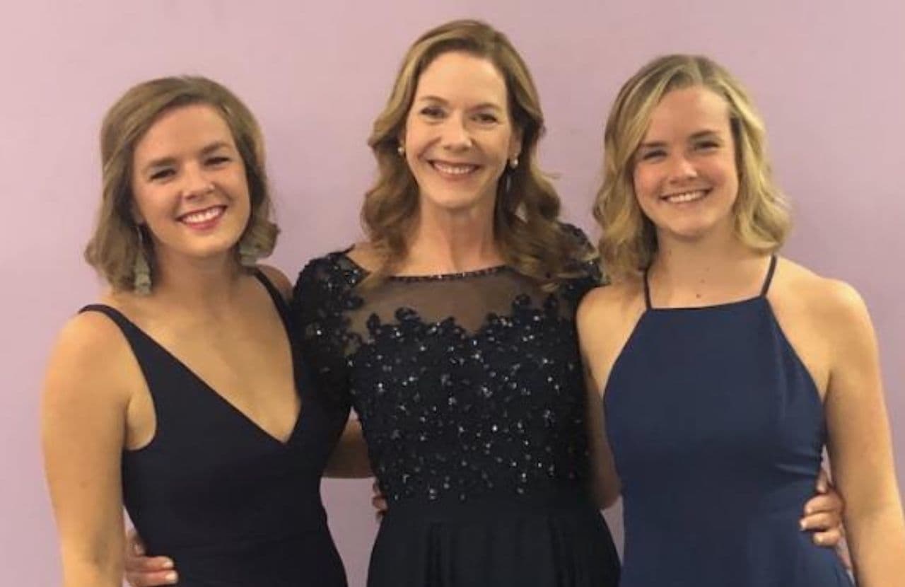 Jennifer Howland stands in between her two daughters with her arms around their waists. They are all smiling brightly and dressed in formal wear on the evening Jennifer received an award..
