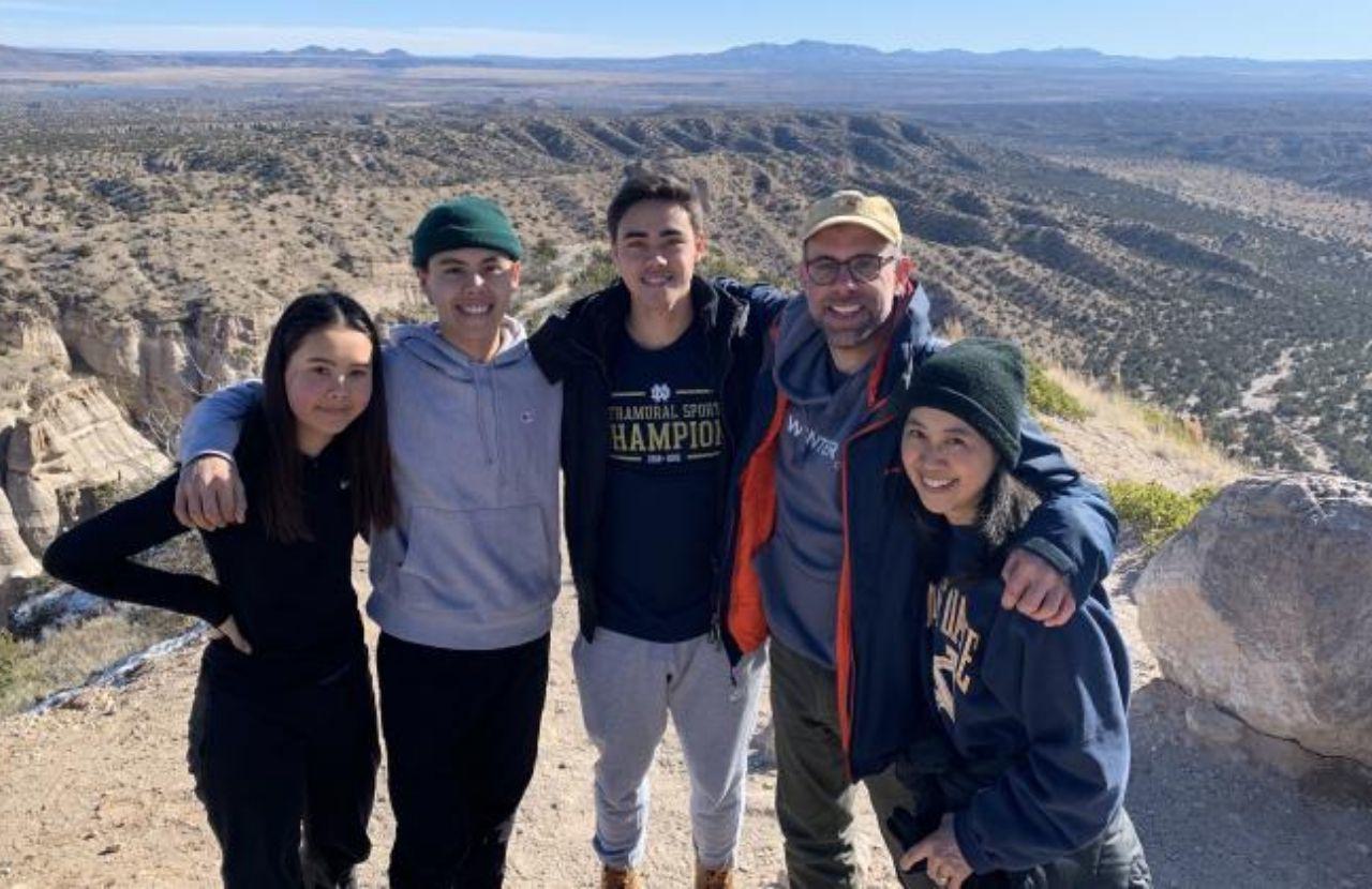 Mari and her family pose in active wear with a great view of a canyon in the backdrop