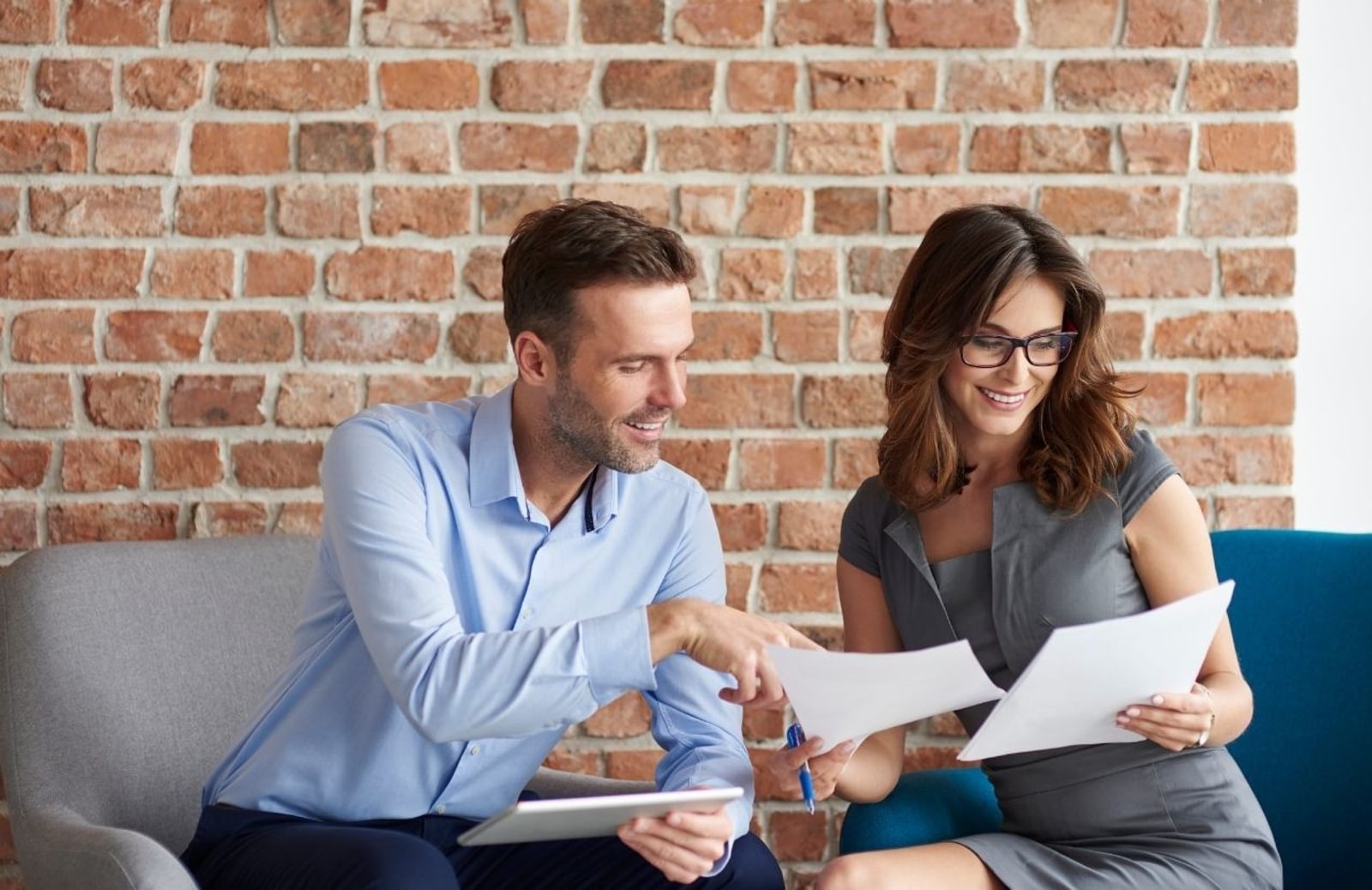 Two professionals smiling while comparing sheets of paper