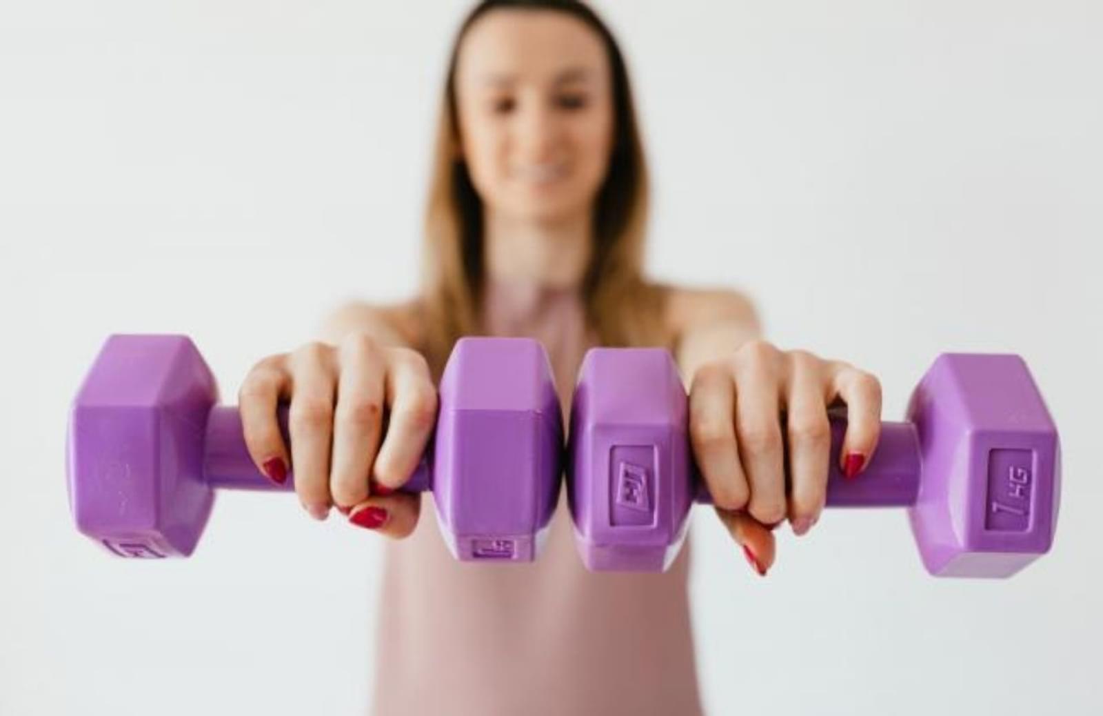 Woman holding two purple handweights in outstretched hands